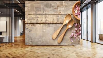 A wooden bowl with pink flowers and two wooden spoons on a wooden table Wall mural