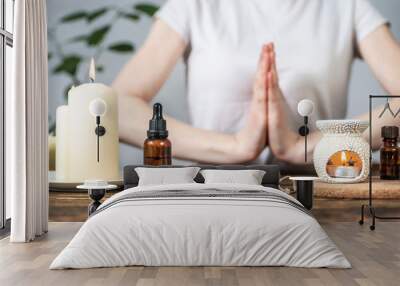 Aroma lamp with essential oils, burning candles and a woman with her hands folded in a namaste pose. Concept of evening and morning rituals, meditation, harmony and balance Wall mural