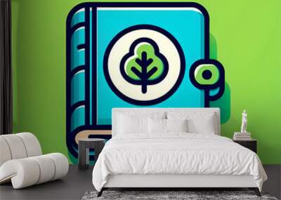 blue book with white circle and leafy tree illustration on cover, resting on light green background Wall mural