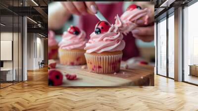 Cupcakes being decorated with pink frosting and chocolate chips, placed on a wooden board in a home kitchen. Wall mural