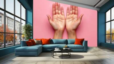 Female hands palms up on pink background close-up with copy space. Wall mural