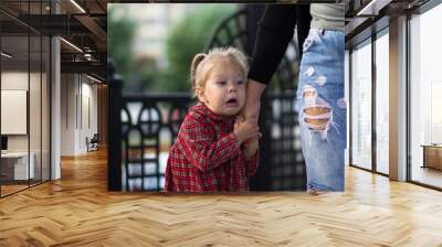 Funny and scared face of the caucasian child of two years old holding mother hand Wall mural