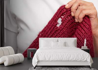 Woman hand holding knitted thing with hole made by moth Wall mural