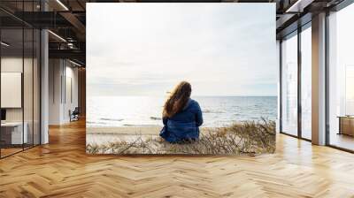 Long-haired curly plus size woman on the seashore, rear view Wall mural