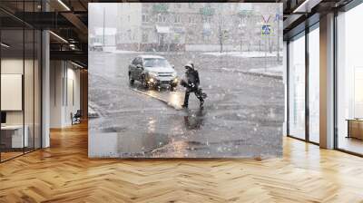 Street of the city, passer-by and snowfall. A man walks down the street in winter, snow falls. Wall mural