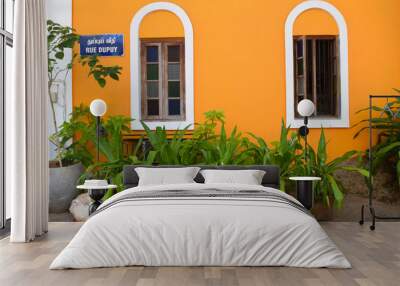 Beautiful french architecture of Pondicherry. Orange painted facade with wooden windows and green plants in clay pots at the street. Wall mural