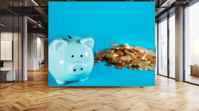 Horizontal image of a blue piggy bank standing on a white desk surface with copy space on the background. Wall mural