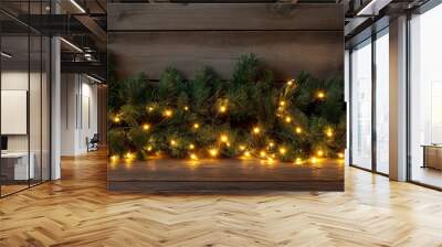 Christmas background with pine branches with warm glowing lights on a dark wood background, festive rustic decor and a cozy winter atmosphere. Place for the text Wall mural