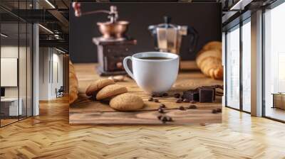 There is hot black coffee with croissants, cookies and chocolate on a wooden table. There is a coffee grinder and a geyser coffee maker In the background Wall mural