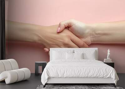 Two hands shaking hands on a pink background. Concept of unity and friendship Wall mural