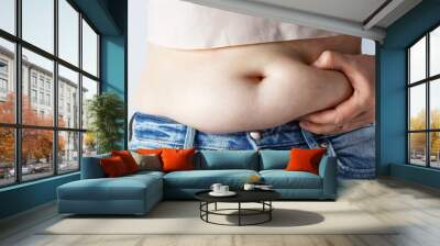 Woman's hand holding excessive belly fat close-up, overweight concept Wall mural