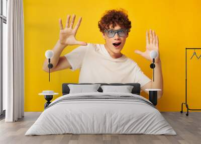 Young curly-haired man in blue glasses white t-shirt fashion modern style isolated background unaltered Wall mural