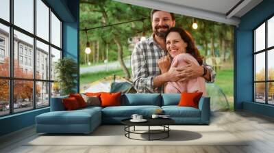 Young married couple feel happy and smile, standing in the forest in the evening Wall mural