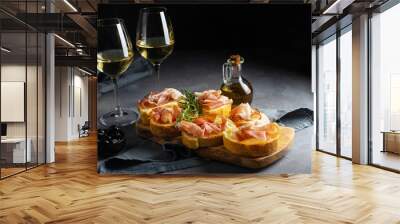 Italian appetiser - bruschetta with prosciutto, white wine, rosemary branch and black olives Wall mural