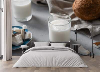 Two glasses of fresh coconut milk next to a blue plate of coconut pieces, emphasizing natural and healthy refreshment. Wall mural