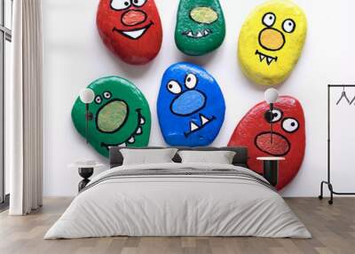 Seven smiling faces of monsters. Painted acrylic pebbles. Wall mural