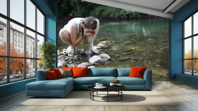 Closeup of a girl washing her face in a river Wall mural