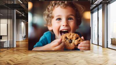 Close up portrait of a happy toddler kid eating a fresh baked cookie, blurred background Wall mural