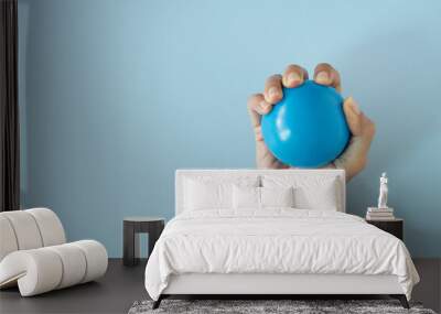 woman hand holding stress ball on blue table background Wall mural