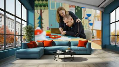 A female psychologist works with an adult boy with autism in the office. Wall mural