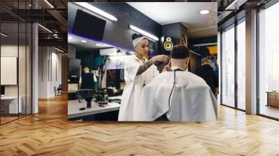 A hairdresser girl cuts a man's hair in a barber shop. Professional men's hair salon. Barbershop. Wall mural