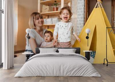 happy mom playing on the floor with two twin girls. Wall mural