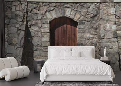 Wooden door in a stone wall. Urban landscape Wall mural