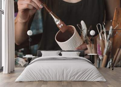 Female sculptor making clay pottery in a home workshop,glazing a clay mug,hands close-up.Small business,entrepreneurship,hobby, leisure concept. Wall mural