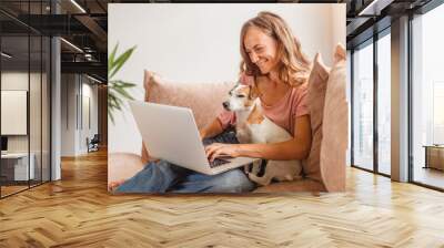 Cheerful woman using silver laptop Wall mural