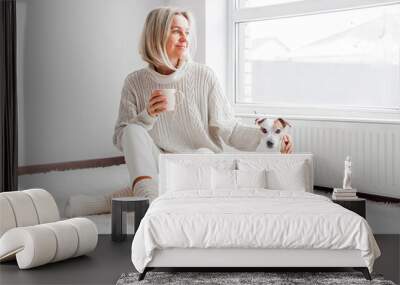 Relaxed, serene adult woman drinking cup of coffee on the sofa in the living room Wall mural