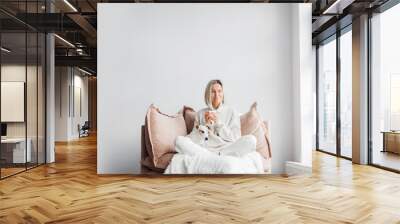 Relaxed, serene adult woman drinking cup of coffee on the sofa in the living room Wall mural