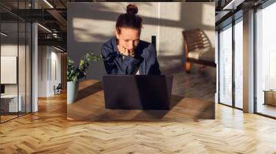 Stressed young woman sitting in front of laptop Wall mural