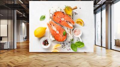 Fresh raw salmon steaks with spices, lemons and pink salt on white wooden board. Top view of fish on white background. Keto recipe. Wall mural