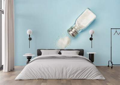 Salt shaker on blue background. Heap of sea salt on the table. Wall mural