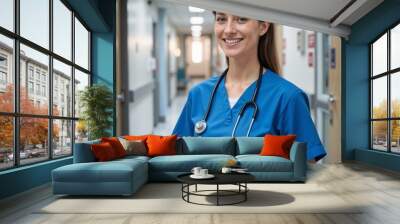 Smiling female nurse holding a tablet in a hospital corridor Wall mural