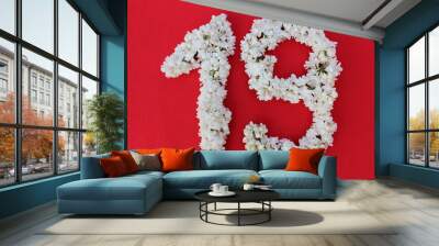 The number 19 is written in white lilac flowers on a red background. The number nineteen is written in fresh flowers, isolated on red. Arabic numeral lined with flowers. Wall mural