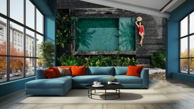 Aerial drone photo of happy Woman in red swimsuit relaxing near private pool with flowers and greenery around, Bali. Tropical background and travel concept. Wall mural