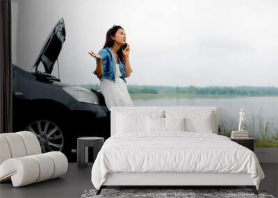 Asian woman standing  on roadside with car breadown using mobile phone Wall mural