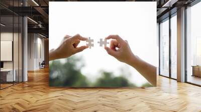 Closeup hands of woman and man connecting jigsaw puzzle Wall mural