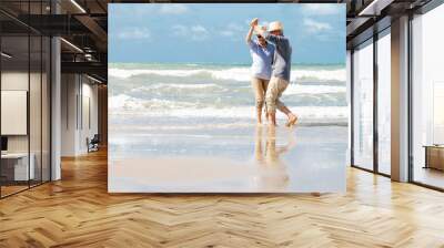 Happy  asian senior couple  dancing  on beach with blue sky background Wall mural