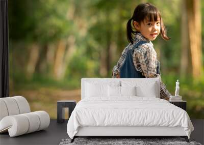 Happy cute asian little girl holding watering can walking  in to park Wall mural