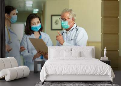 Professional  doctors  wearing mask consult while walking  at hospital Wall mural