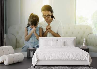 woman and little girl  praying on holy bible Wall mural