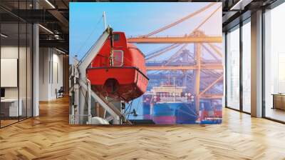 Lowering orange lifeboat, Safety lifeboat on deck of bulk ship in port. Wall mural