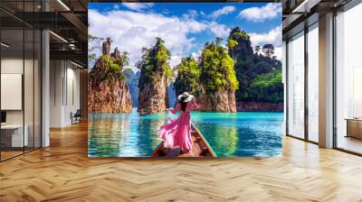 Beautiful girl standing on the boat and looking to mountains in Ratchaprapha Dam at Khao Sok National Park, Surat Thani Province, Thailand. Wall mural