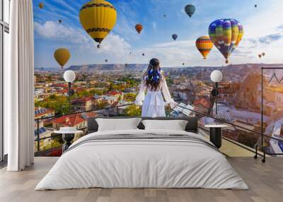 Beautiful girl standing on the hotel and looking to hot air balloons in Cappadocia, Turkey. Wall mural