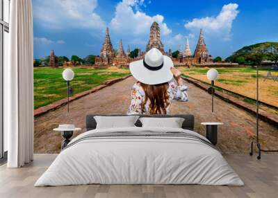 Woman holding man's hand and leading him to Ayutthaya Historical Park, Wat Chaiwatthanaram Buddhist temple in Thailand. Wall mural