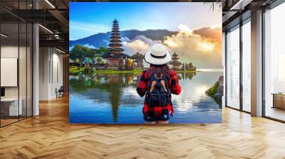 Woman traveler with backpack looking to pura ulun danu bratan temple in Bali, indonesia. Wall mural