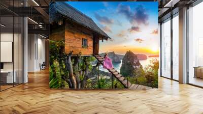 Young girl on steps of house on tree at sunrise in Nusa Penida island, Bali in Indonesia. Wall mural