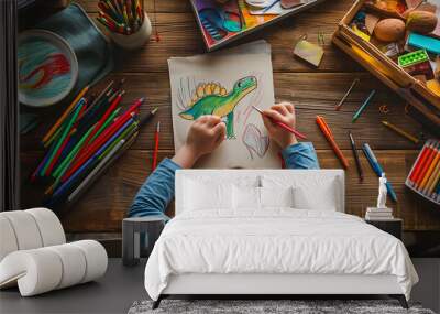 A child sitting at a table with art supplies, drawing a dinosaur on paper. Wall mural